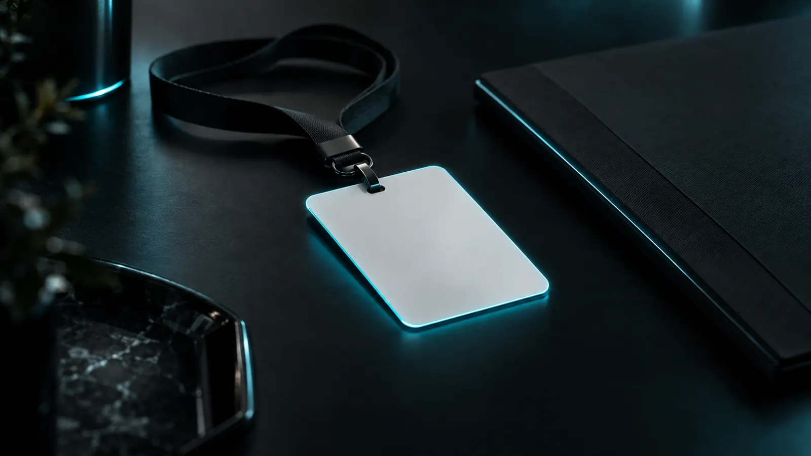 A blank staff identity card on a lanyard, lit with a cyan edge on a black desk.